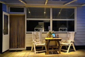 Eine überdachte Terrasse mit zwei Schaukelstühlen, einem Tisch und einem Laptop.