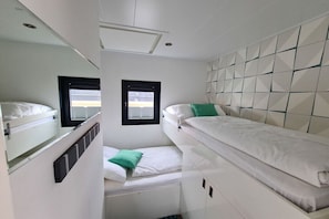 A compact room with bunk beds, a small window, and a white tiled wall.