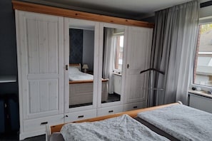 A bedroom with a bed, wardrobe, and a window with curtains. - Holiday apartment with 1 bedroom (Borkum)