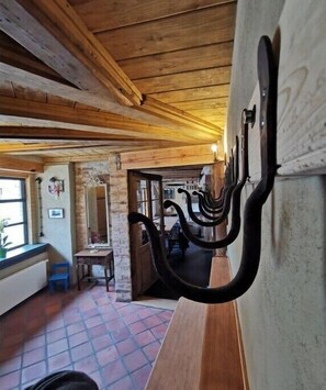 Ein rustikales Interieur mit freiliegenden Holzbalken, einer Backsteinwand und einer Bank mit Kleiderhaken.