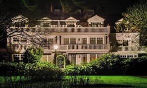 Un hotel de varios pisos con fachada simétrica, balcones e ingreso bien iluminado.
