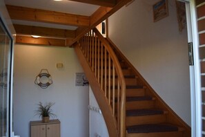 Eine hölzerne Treppe mit Geländer, einem Topfpflanzen und einer Wandleuchte.