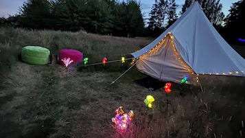 A tent with string lights and a green bean bag chair.
