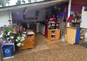 A garage with a wooden workbench, a red refrigerator, and a blue recycling bin.