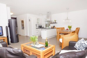 Ein modernes Wohnzimmer mit Sofa, Couchtisch und Essbereich.
