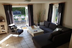 A living room with a sofa, a coffee table, and a dining area with chairs and a table. - Zomprus holiday home (Kamperland)