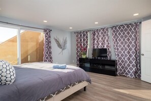 Ein Schlafzimmer mit Bett, Fernseher, Kommode und einer Schiebetür.
