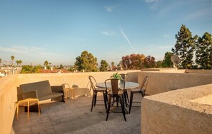 Eine Dachterrasse mit rundem Tisch, Stühlen, einer Couch und einer Satellitenschüssel.