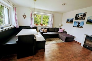 Ein moderner Wohnraum mit Esstisch, Sofa und Kamin.