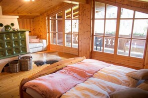 A wooden cabin room with a bed, a green chest of drawers, and large windows. - Zirbenchalet Eggriedl (Großarl)