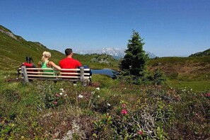 A couple sitting on a bench overlooking a lake with mountains in the background. - Zirbenchalet Eggriedl (Großarl)