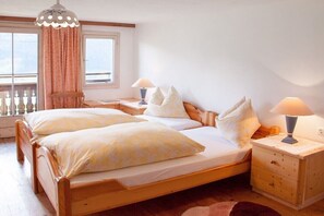 A double bed with two nightstands, a window with curtains, and a hanging light fixture. - Holiday home in Uttendorf with Wi-Fi (Uttendorf)