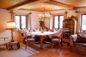 A cozy room with a wooden dining table surrounded by cushioned seating, a chandelier, and a glass display cabinet. - Holiday home in Uttendorf with Wi-Fi (Uttendorf)