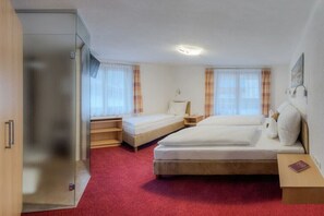 Ein Zimmer mit zwei Betten, einem Schrank und einem kleinen Tisch.