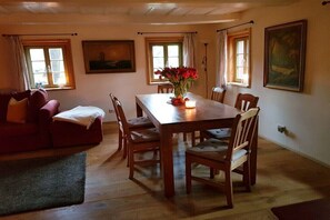 Ein Essbereich mit einem Holztisch und Stühlen, einer Blumenvase und einem Bild an der Wand.