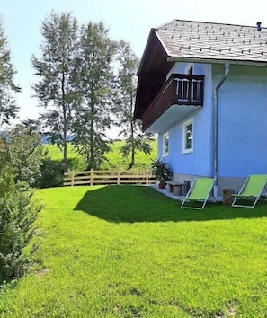 Ein Haus mit geneigtem Dach, einem Balkon und einem gepflegten Rasen.