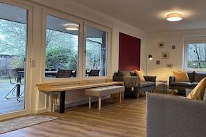 Ein modernes Wohnzimmer mit großen Fenstern, einer hölzernen Bank und einem Sofa.