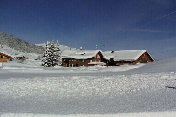 A snow-covered landscape with a wooden cabin and a tree. - Holiday home in Mittelberg with Wi-Fi (Mittelberg)