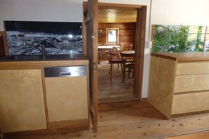 A wooden interior with a kitchen area, a dining table, and chairs. - Holiday home in Mittelberg with Wi-Fi (Mittelberg)