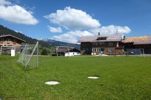 A grassy field with a soccer goal, a building with a metal roof, and mountains in the background. - Holiday home in Mittelberg with Wi-Fi (Mittelberg)