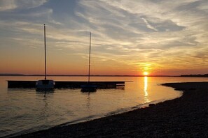 A sunset over a calm body of water with two boats moored at a dock. - Holiday apartment with 2 bedrooms (Chieming)
