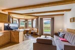 A wooden interior with a kitchen, dining area, and living room, featuring large windows and a view of the outdoors. - Apartment in Leutasch with swimming pool (Leutasch)