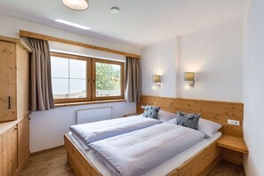 A bedroom with two beds, wooden headboard, a window with curtains, and wall-mounted lights. - Apartment in Leutasch with swimming pool (Leutasch)