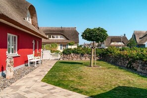 A red building with a thatched roof, a stone wall, and a small tree in the yard. - Holiday home with 4 bedrooms (18445 Kramerhof, Deutschland OT Parow)