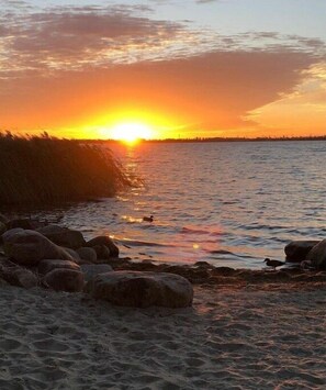 A sunset over a body of water with rocks and a bird. - Holiday home with 4 bedrooms (18445 Kramerhof, Deutschland OT Parow)
