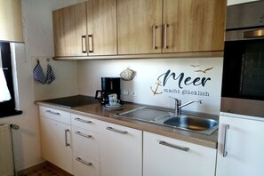 A kitchen with wooden cabinets, a stainless steel sink, and a coffee maker. - Hansmeier in the Eckwarderhörne holiday village (Butjadingen)