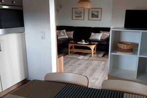 A compact living space with a kitchenette, a sofa, a small table, and a TV on a stand. - Hansmeier in the Eckwarderhörne holiday village (Butjadingen)