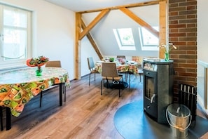 A dining area with wooden beams, a brick fireplace, and a table with a floral tablecloth. - Holiday rooms in Schlepzig with barbecue (Schlepzig)