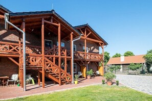 A brick building with wooden beams, a staircase, and outdoor seating. - Holiday rooms in Schlepzig with barbecue (Schlepzig)
