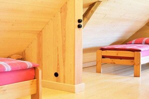 Ein Schlafzimmer im Schlafgeschoss mit zwei Betten, einer geneigten Decke und Holzboden.