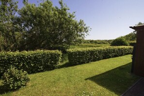 A well-maintained garden with neatly trimmed hedges and a wooden structure. - Holiday apartment with 2 bedrooms (Nordseebad Borkum)