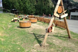 Ein Spielplatz mit Holzgerüsten, Picknicktischen und einer Schaukel aus Holz.