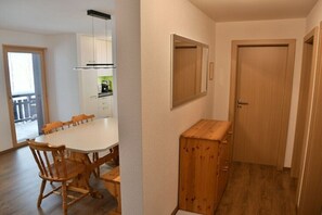 Eine kleine Küche mit Esstisch, Stühlen, einem Holzschrank und einem Spiegel an der Wand.