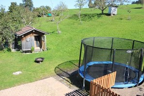 Ein Rasen mit Trampolin und Holzkonstruktion.