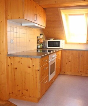 Eine Küche mit Holzausstattung, einer Mikrowelle und einem Fenster.
