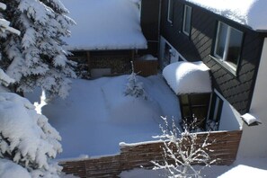 Ein mit Schnee bedecktes Wohngebiet mit einem Haus, einem Holzzaun und einem Baum.