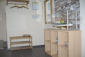 Ein Zimmer mit einer hölzernen Bank, einer Vitrine mit einem Modellschiff und einer Steinwand.