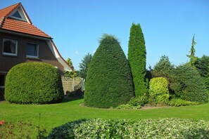 Ein gepflegter Garten mit ordentlich geschnittenen Hecken und ein Haus mit rotem Dach.