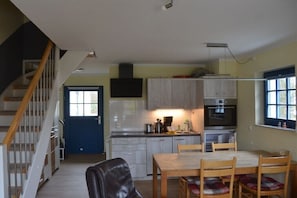 Una cocina con una mesa de comedor y sillas, una escalera y una puerta azul.