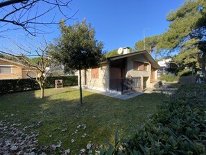 Ein Wohnhaus mit gepflegtem Rasen, einem kleinen Baum und einem Dach mit Satellitenschüssel.
