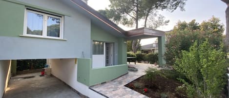 A modern house with a flat roof, a covered porch, and a small garden area.