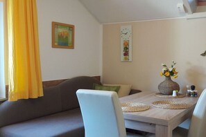 Ein Essbereich mit einem Holztisch, Stühlen, einer Vase mit Blumen, einer Uhr und einem Gemälde an der Wand.
