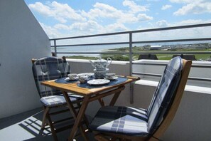 Ein Balkon mit Tisch, der für Tee gedeckt ist, zwei Stühlen und Blick auf die Landschaft.