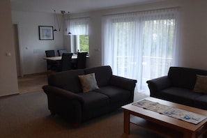 Ein Wohnzimmer mit zwei Sofas, einem Couchtisch und einem Essbereich mit Stühlen und einem Tisch.