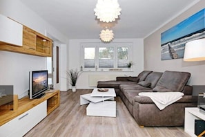 Ein modernes Wohnzimmer mit Sofa, Fernseher und Essbereich.