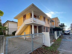 Um edifício residencial de vários andares com varanda, escadaria e portão.
